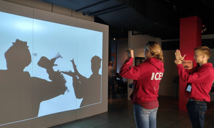 two teens making hand shadow characters on big screen