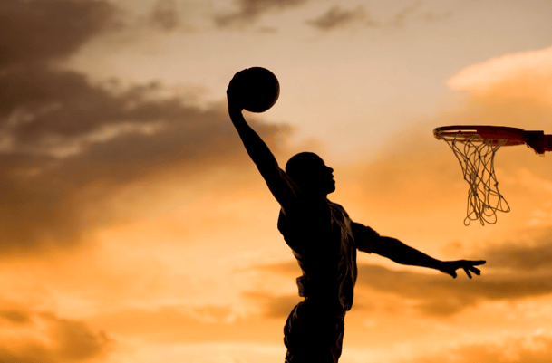 silhouhette of boy dunking basketball