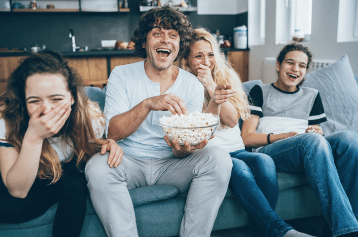 4 people laughing and watching tv