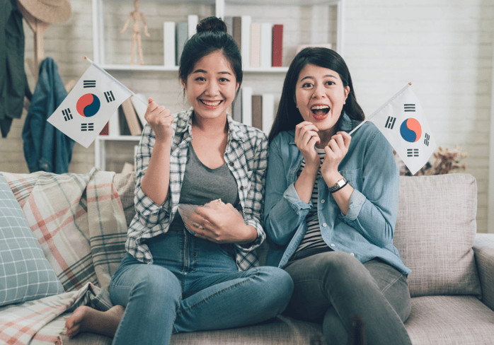 2 smiling Korean women holding flags