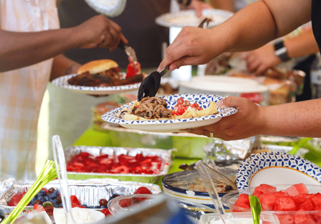 people serving plates at potluck