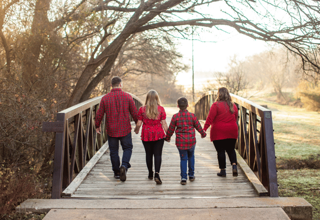 family holding hands walking across bridge