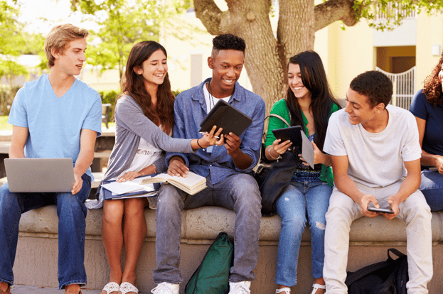 group of teens sitting on a wall