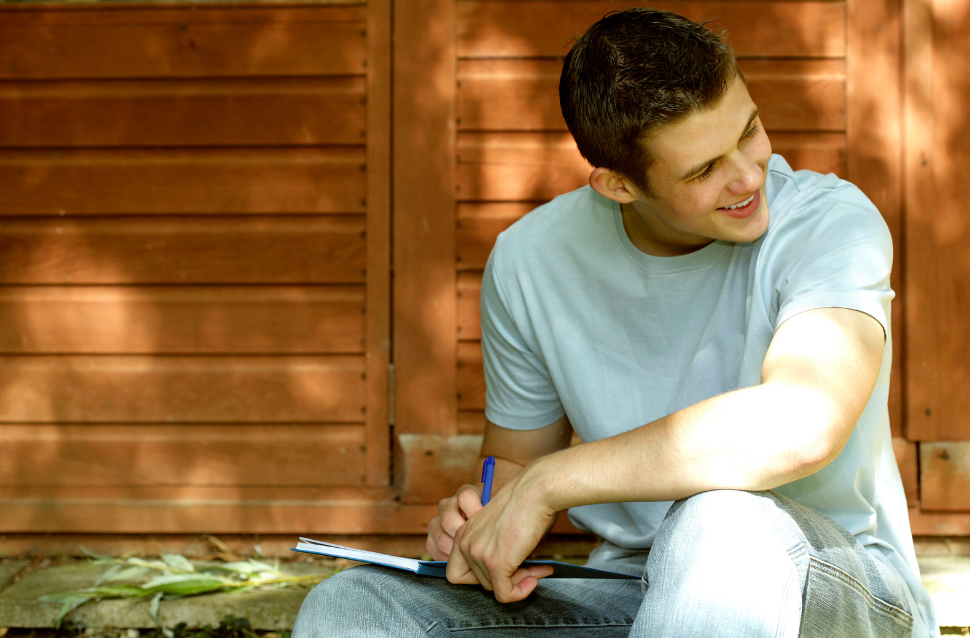 smiling teen boy writing in journal