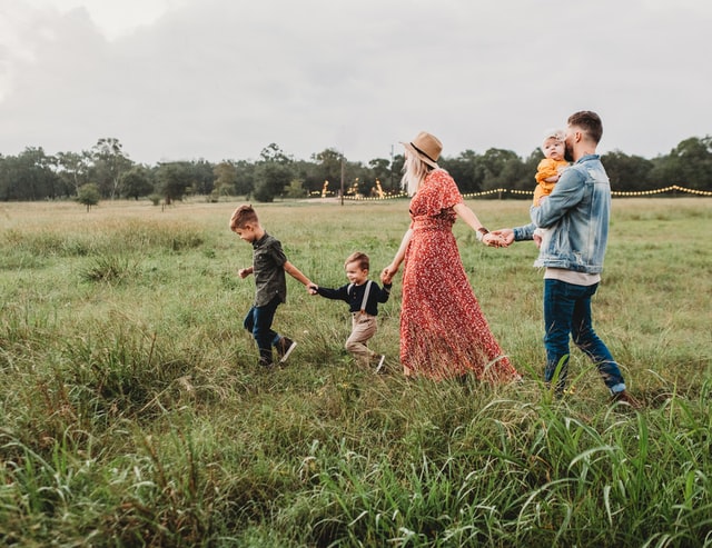 a mother, father and small children walking through a field