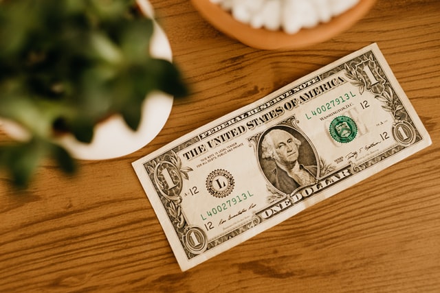 a US one dollar bill laying on a wood table