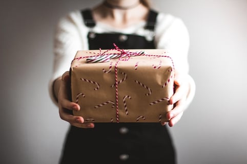 girl holds package wrapped in candy cane wrapping