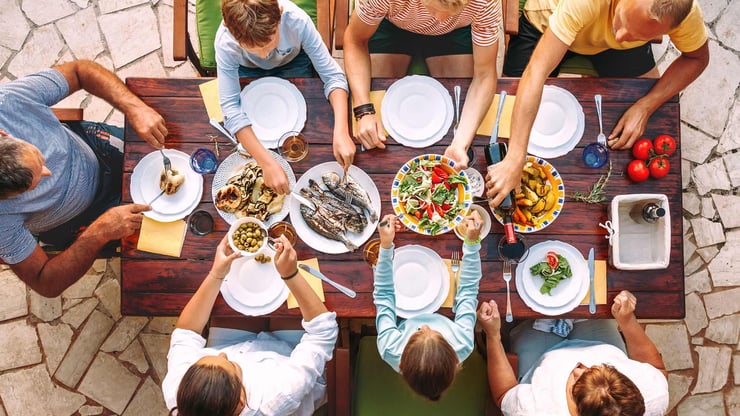 large family eating big meal together around a wooden table