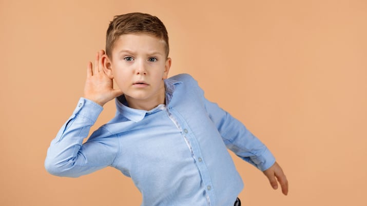 little boy with hand to ear listening