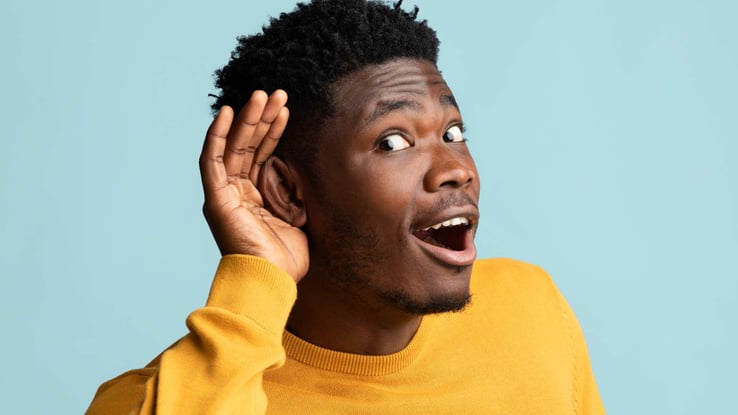 man with hand held to ear to show he is listening