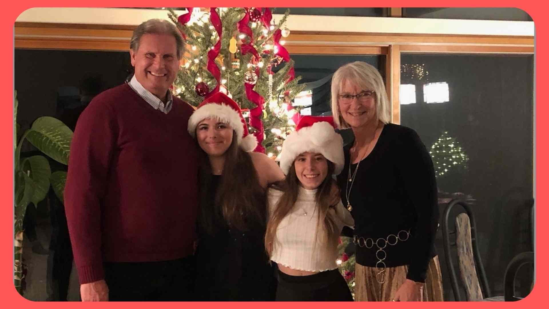 mother father and daughters in front of Christmas tree