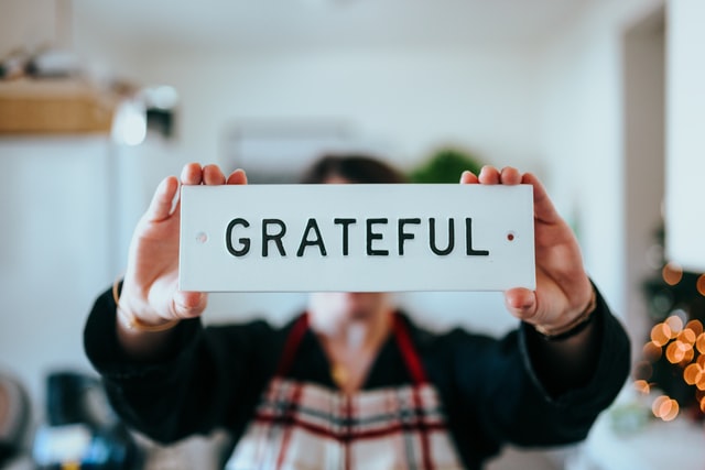 a teenage boy holding a metal sign that says gratitude