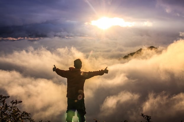 a teenage boy staying triumphantly on a mountaintop