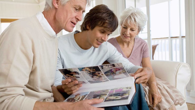 older couple looking at photo album with teenager boy