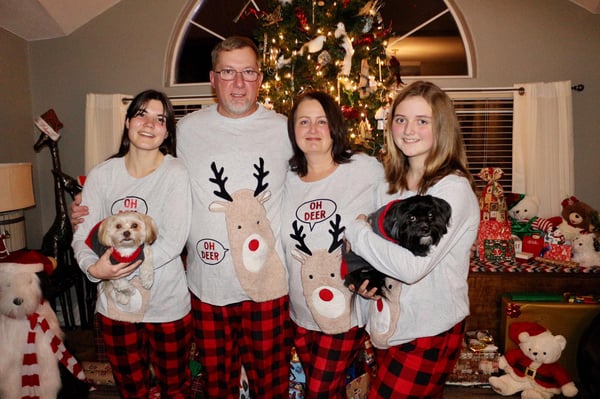 parents and two daughters wearing Christmas pijamas in front of Christmas tree