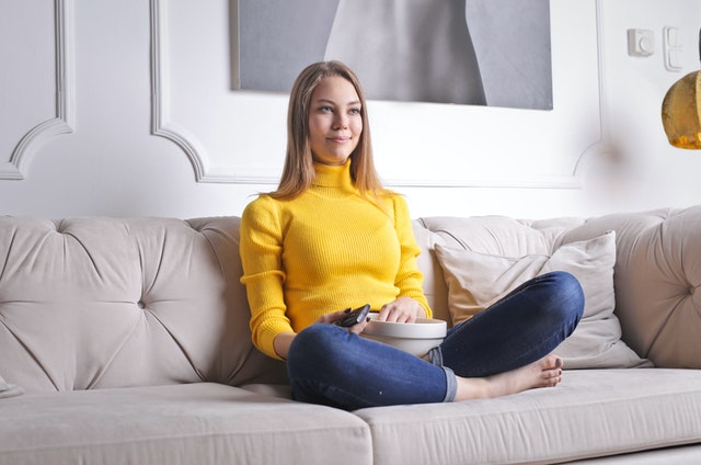 teenage girl sitting on sofa watching tv