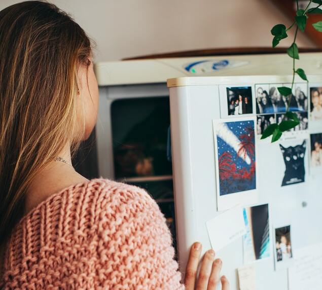 teenage girl opening fridge looking inside