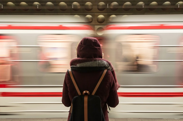 teenager waits for the subway with back to camera