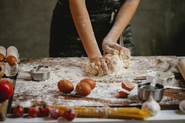 hands kneading pasta on floured board