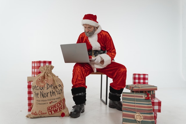 santa making christmas list with computer