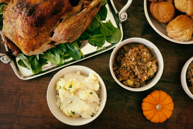 a thanksgiving dinner with turkey, stuffing, mashed potatoes and a small pumpkin
