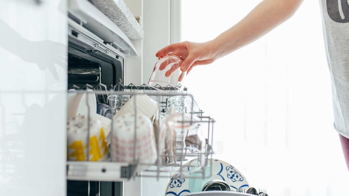 putting a glass into the dishwasher