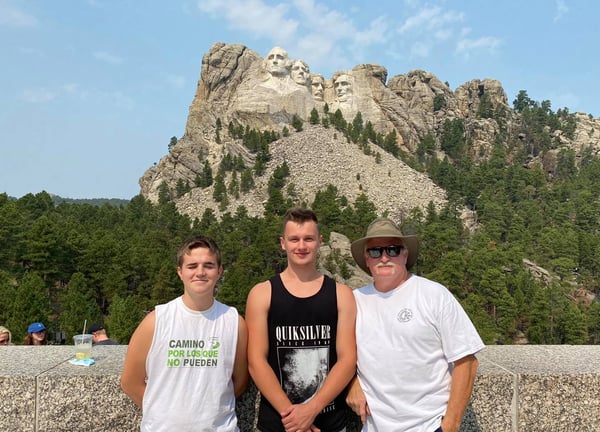 boys and host dad in front of Mt Rushmore