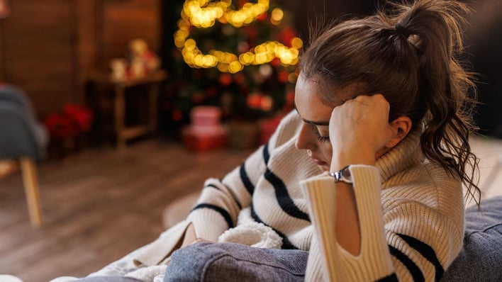 sad teenage girl sitting on sofa by christmas tree