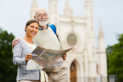 senior couple holding map in front of castle