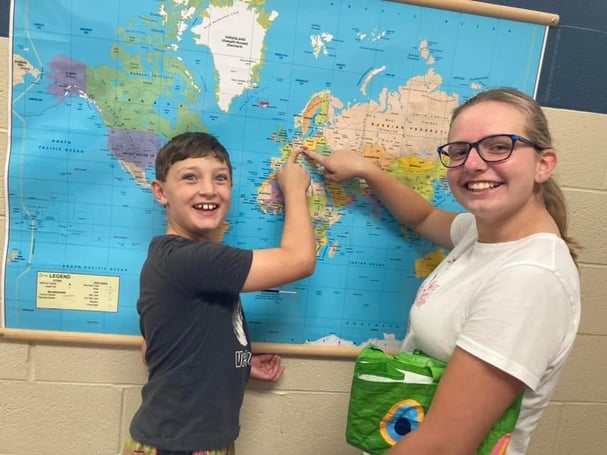 young boy and teen girl pointing to world map
