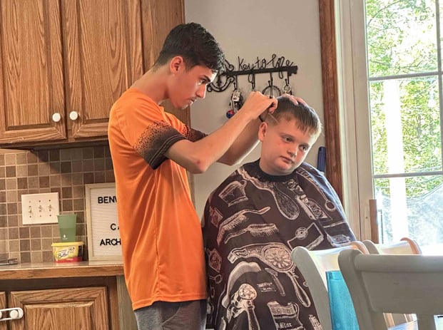 teen boy giving younger boy a haircut