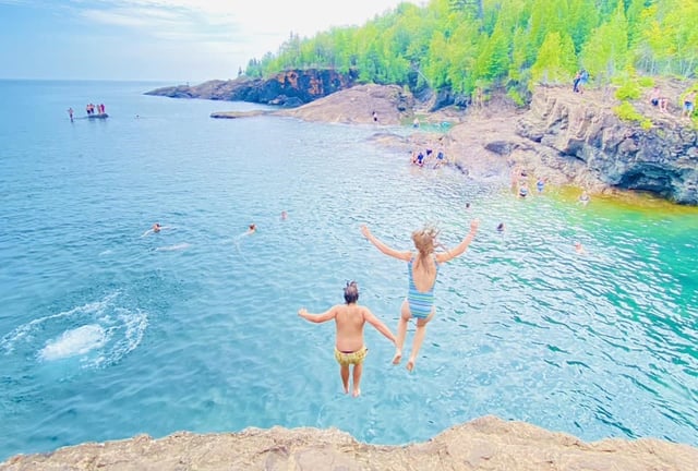 two teens jumping off a cliff into water