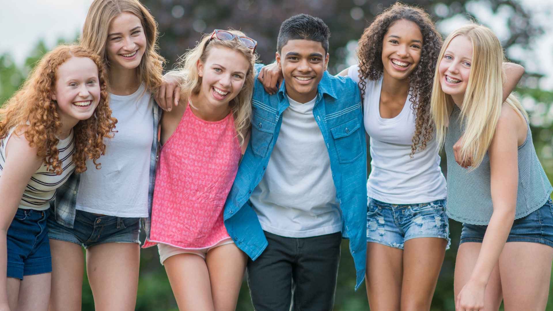 six teenagers standing together with arms around shoulders