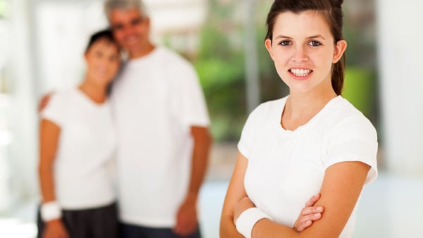 smiling teenage girl with parents in background