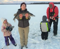 teen girl holding a fish in the snow