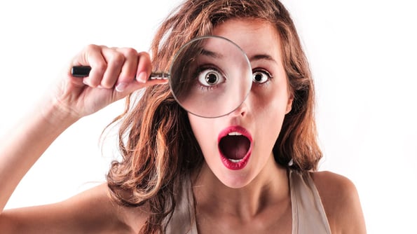 surprised woman looking through a magnifying glass