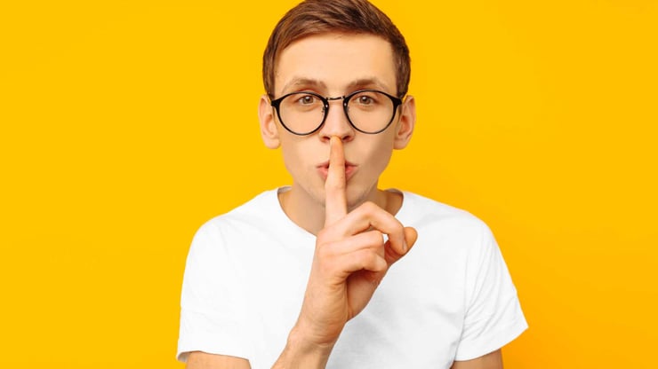 teen boy with finger over mouth to say be quiet