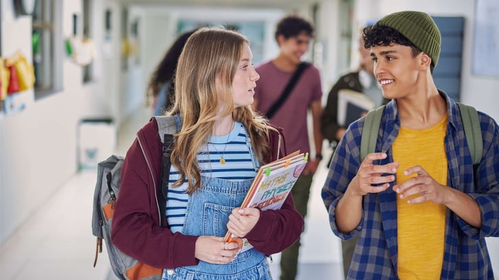 teen girl and guy walking down the hall at high school