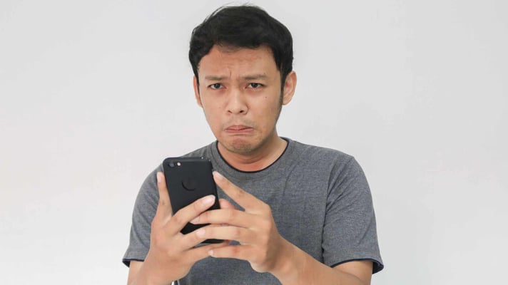 teenage boy looking at phone with sad face