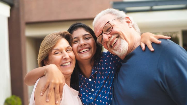 teenage girl smiling and hugging older parents