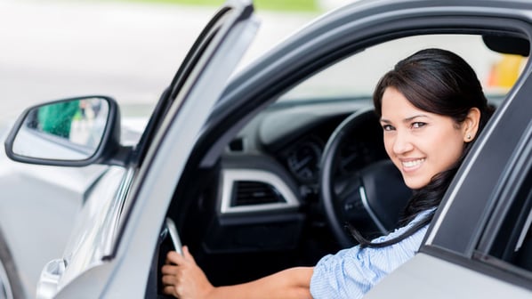teenage girl smiling from drivers seat in car