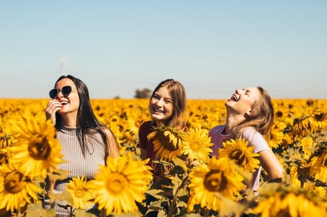 teenage girls smiling in sunflower field showing cultural adaptation and overcoming culture shock and transition stress