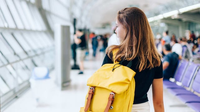 teenager with yellow backpack walking through airport