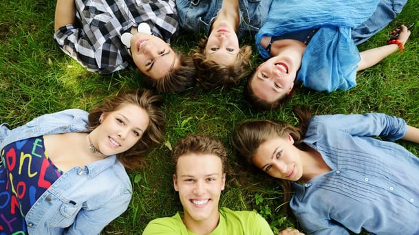 teenagers in a circle lying on the ground smiling