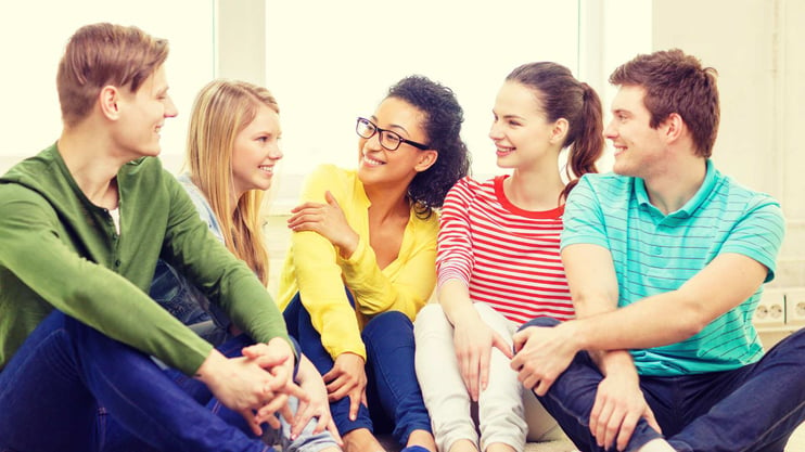 teenagers sitting together smiling at each other