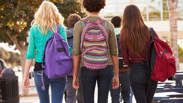 three high school students walking with backpacks
