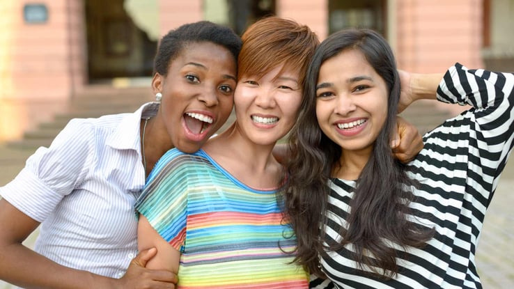 three women of different ethnic backgrounds smiling together