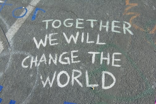 together we will "change the world" written in chalk on the street