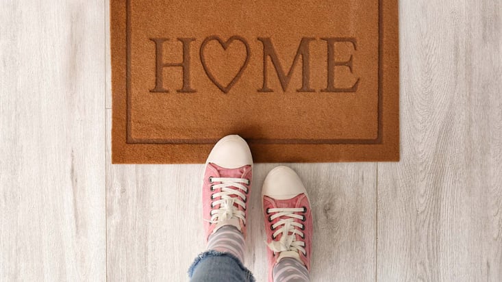two feet standing by a welcome mat