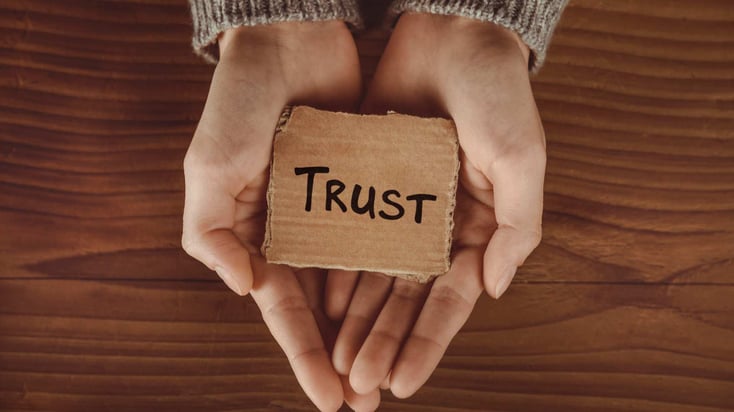 two hands holding a sign that says trust